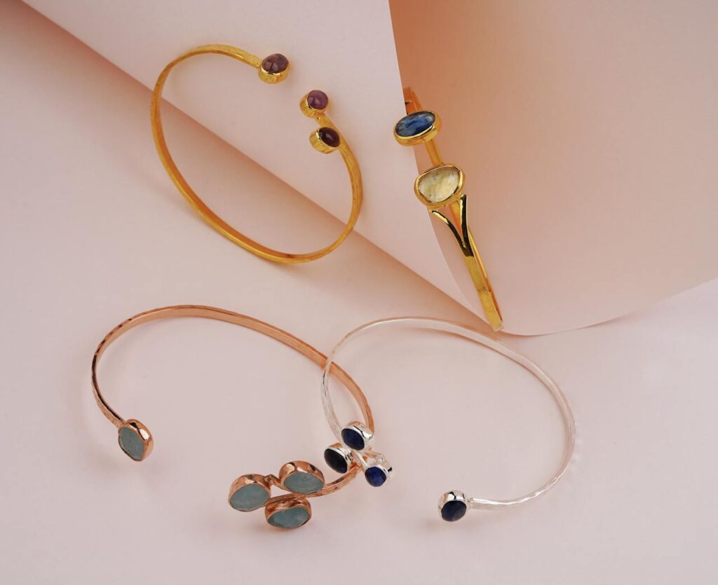 Stylish gemstone bracelets elegantly displayed on a pastel pink backdrop, highlighting luxury and elegance.